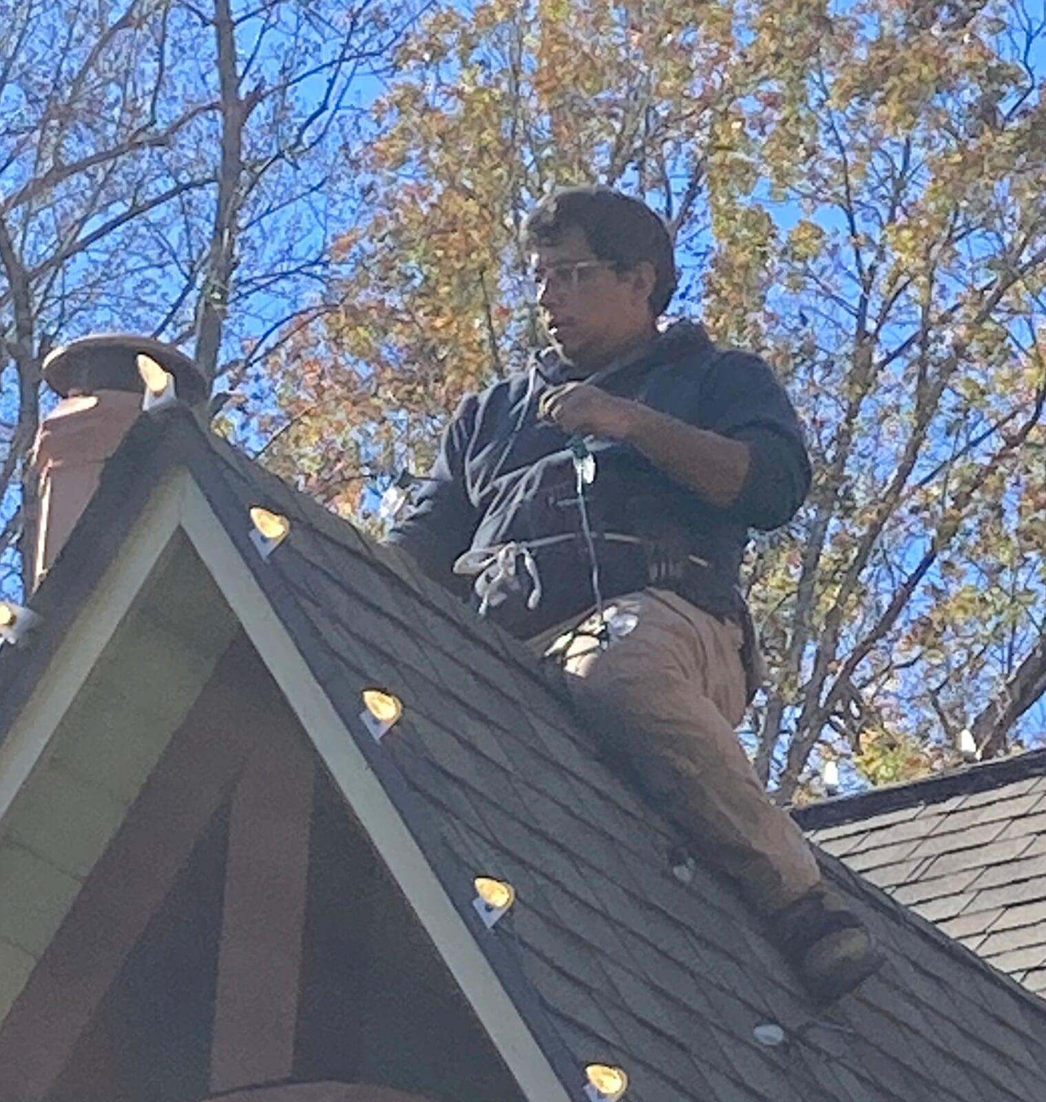 Image of someone on a roof taking down christmas lights