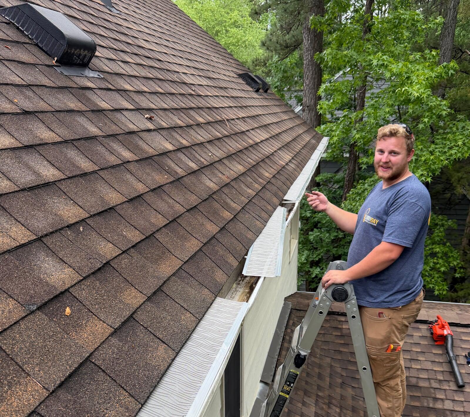 A technician installing gutter guards on a house