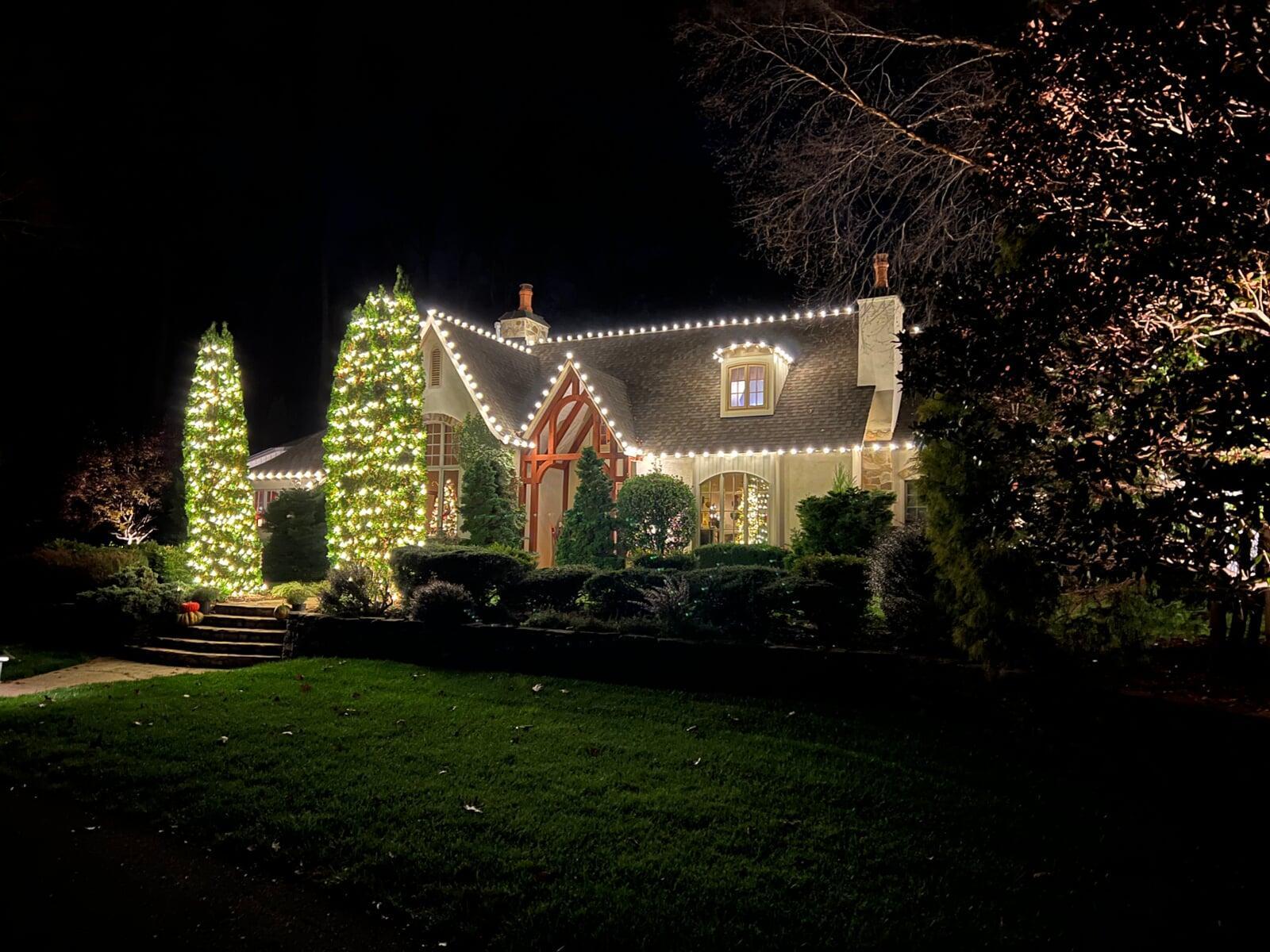 Home with roofline lighting with two trees in the front with lights